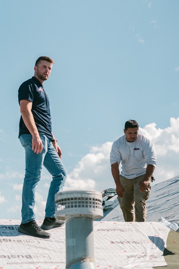 Two Olympus roofers walking across a rooftop in progress